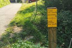 Au panneau, suivre la voie goudronnée et continuer tout droit en direction des habitations. Celle-ci tournera sur la gauche et passe le long de quelques maisons. (7 août 2024)