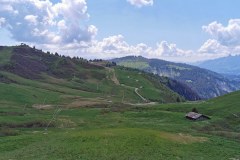Suivre les canons à neige jusqu’à la piste que l'on voit au loin. À noter la possibilité de prendre le sentier que l'on voit  bien à droite derrière le chalet  (31 mai 2020)